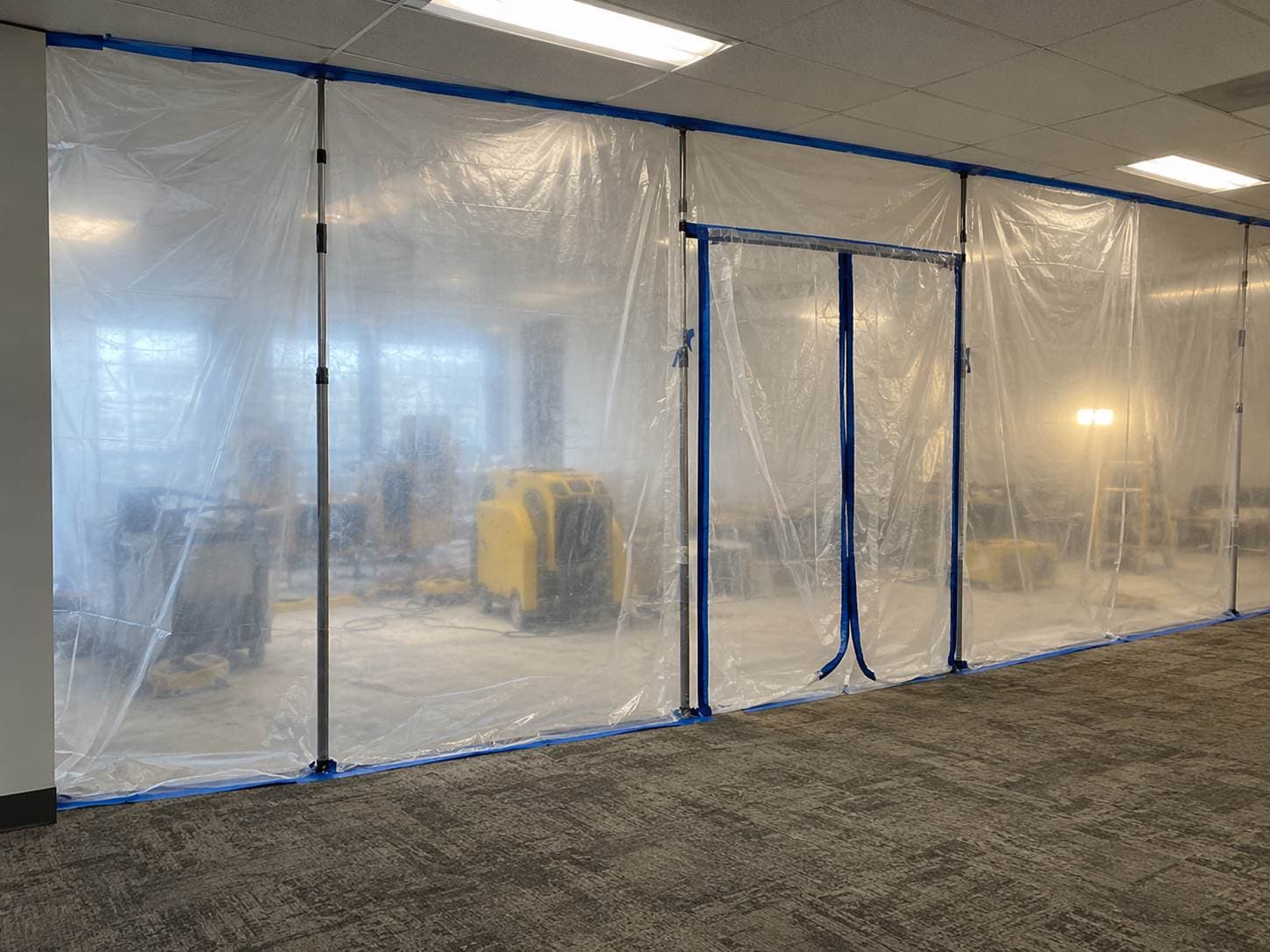 Plastic containment wall dividing a closed work area from an open retail floor