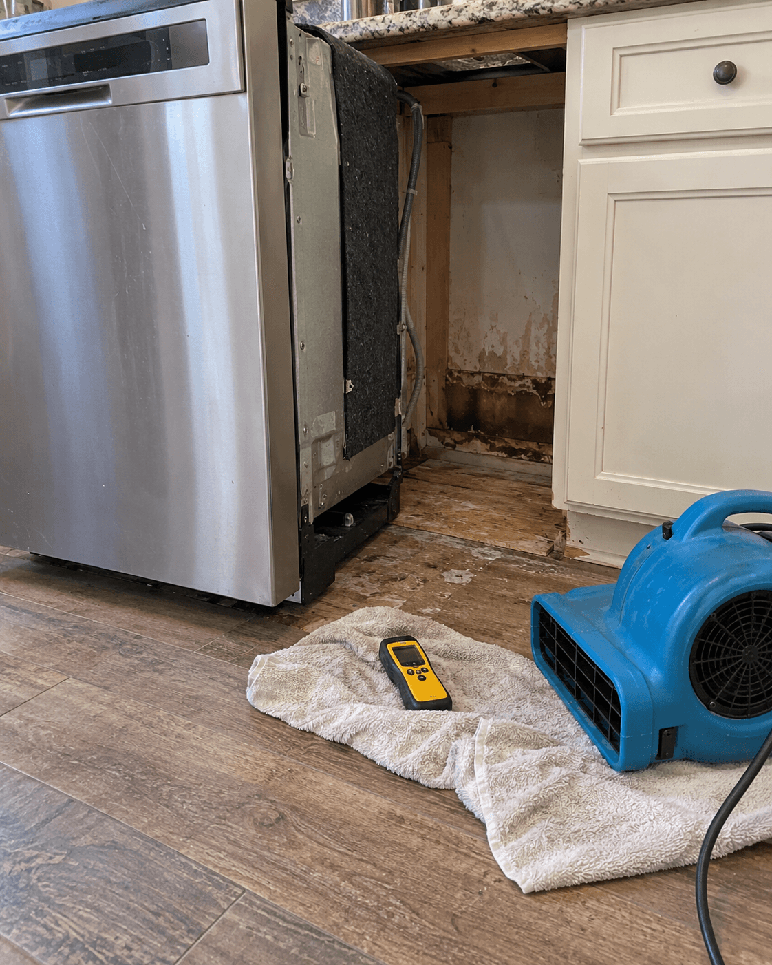 Pulled-out dishwasher with a damp cabinet base and moisture meter