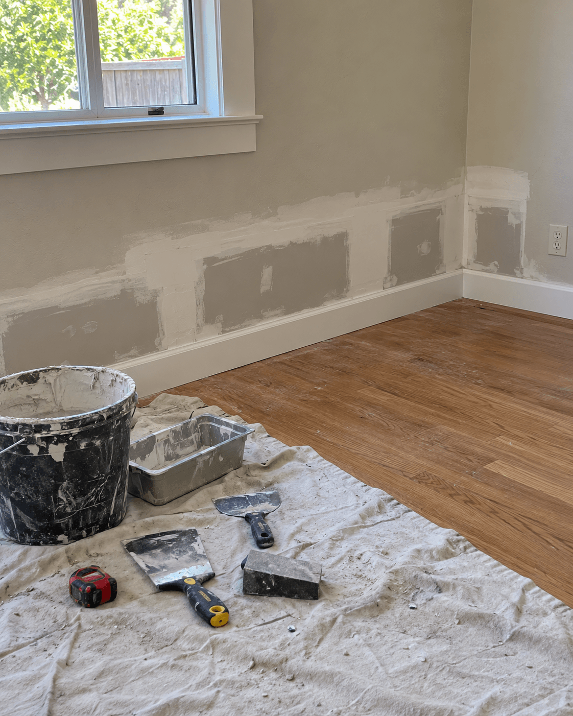 Patched wall and new baseboard during restoration repairs